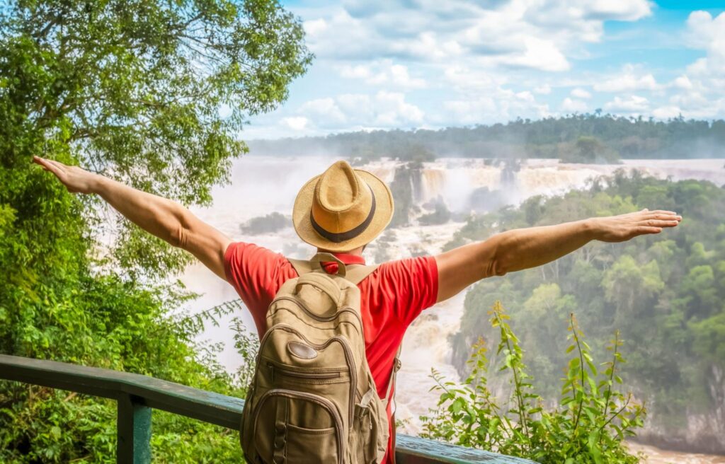 Homem de costa se braços abertos, em um pier nas Cataratas do Iguaçu