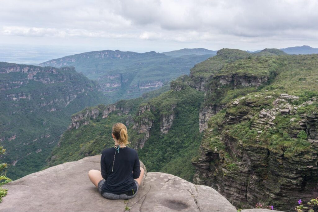 Mulher sentada de costas, olhando a vista de um dos picos da Chapada Diamantina