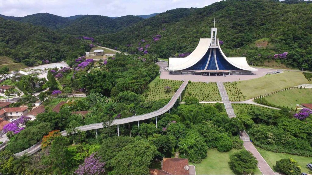 Santuário de Madre Paulina, de arquitetura contemporânea, com estrutura branca e azul cujo formato lembra uma tenda. Ao redor, serras verdes e trechos arborizados.