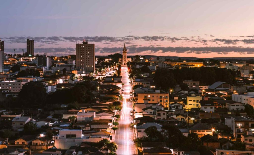 Panorâmica da cidade de Araxá iluminada, mostrando prédios e casas durante a noite.