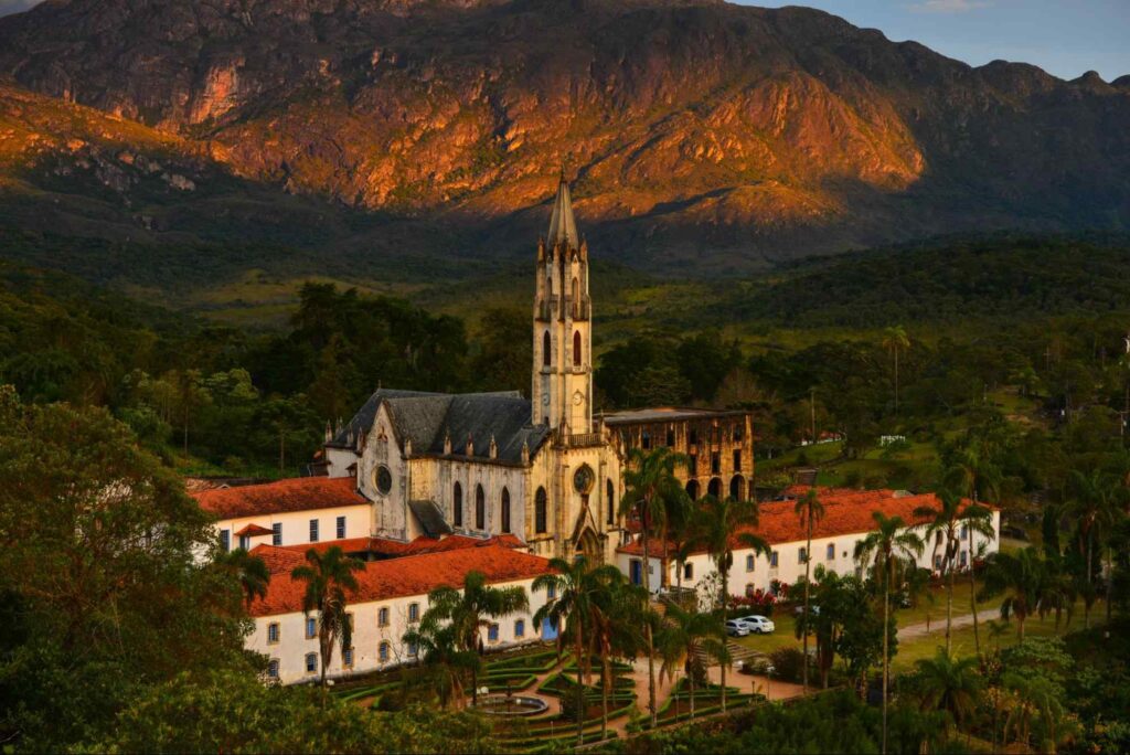 Igreja do Santuário da Carcaça no centro da imagem, rodeada por prédios brancos que compõem o santuário, e mata nativa ao redor. Ao fundo, uma cadeia de montanhas.