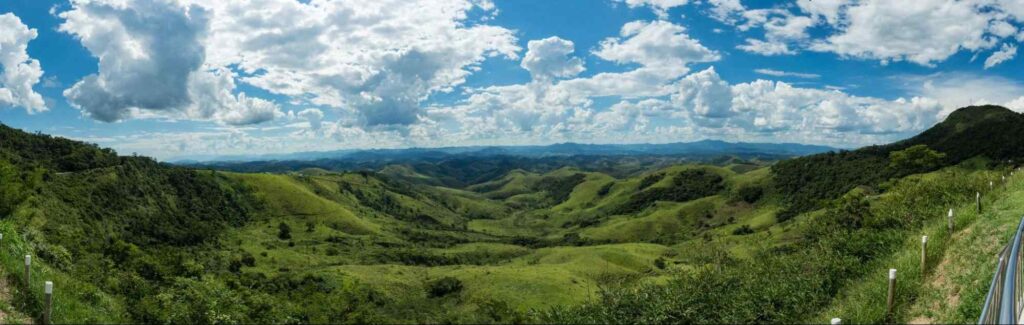 Paisagem de montanhas verdes em contraste com céu azul e nuvens brancas. Local: Serra da Beleza.