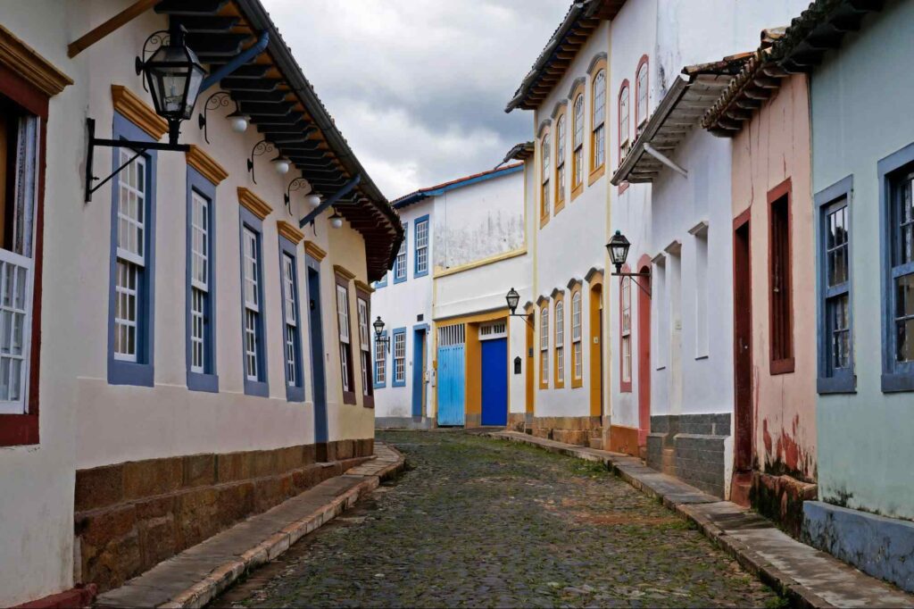 Rua das Casas Tortas em São João del Rei. Chão de paralelepípedo com casas coloridas em estilo colonial.