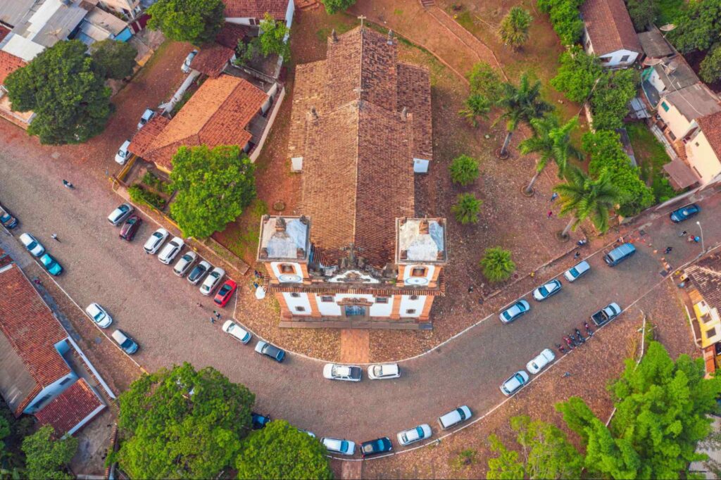 Vista áerea da Igreja Nossa Senhora do Carmo, principal igreja da cidade. Ao redor estão algumas casas e vários carros estacionados