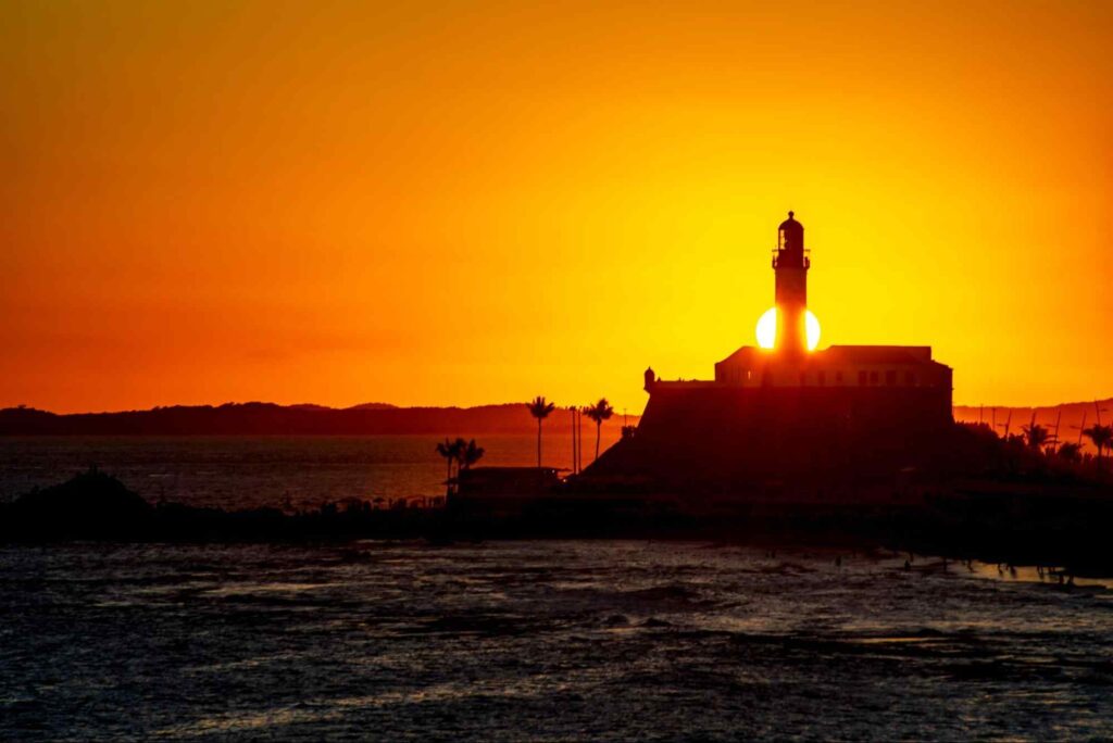 Farol ao longe no fim de tarde com céu amarelado.