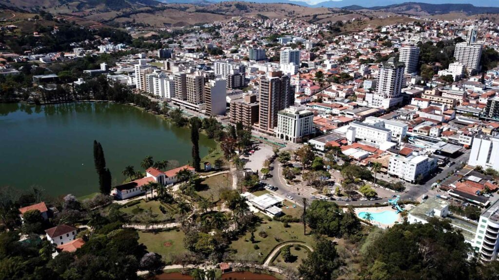 Vista aérea da cidade de São Lourenço MG, mostrando parte do Parque das Águas, prédios, casas e as montanhas da Serra da Mantiqueira ao fundo.