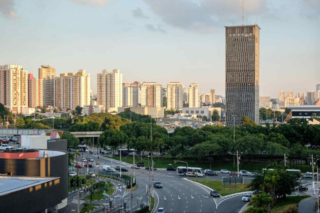 Paisagem urbana de São Bernardo, composta por prédios altos de fachada clara. Em primeiro plano, há pistas com alguns carros e ruas são arborizadas.