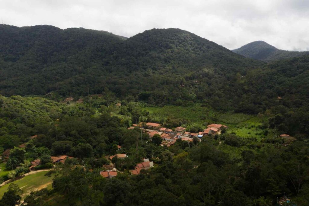 Vista aérea de Guaramiranga, no Ceará. Telhados avermelhados das casas e outras construções, aglomeradas em meio à vegetação composta por árvores de várias espécies.