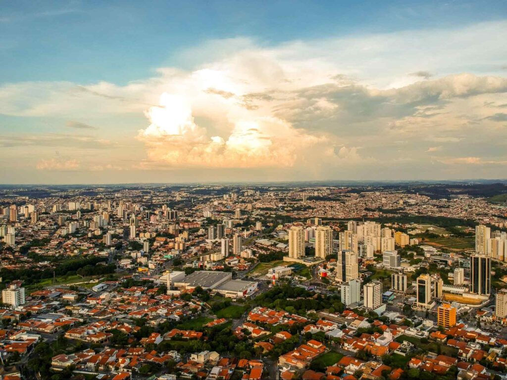 Vista aérea de Sorocaba, composta majoritariamente por casas, enquanto outras têm construções mais variadas, incluindo prédios altos. A paisagem urbana é bem arborizada.