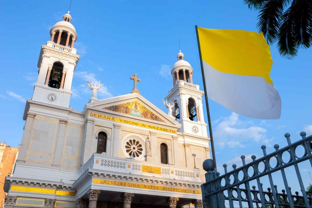 Fachada da Basílica Santuário Nossa Senhora de Nazaré, em Belém. A construção é pintada em branca com adornos dourados e tem um estilo arquitetônico neoclássico.