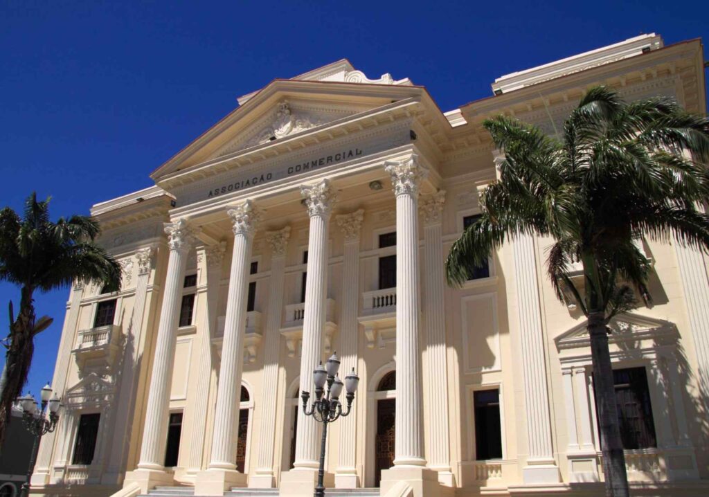 Fachada branca na Associação Comercial de Maceió, com colunas brancas e imponentes.