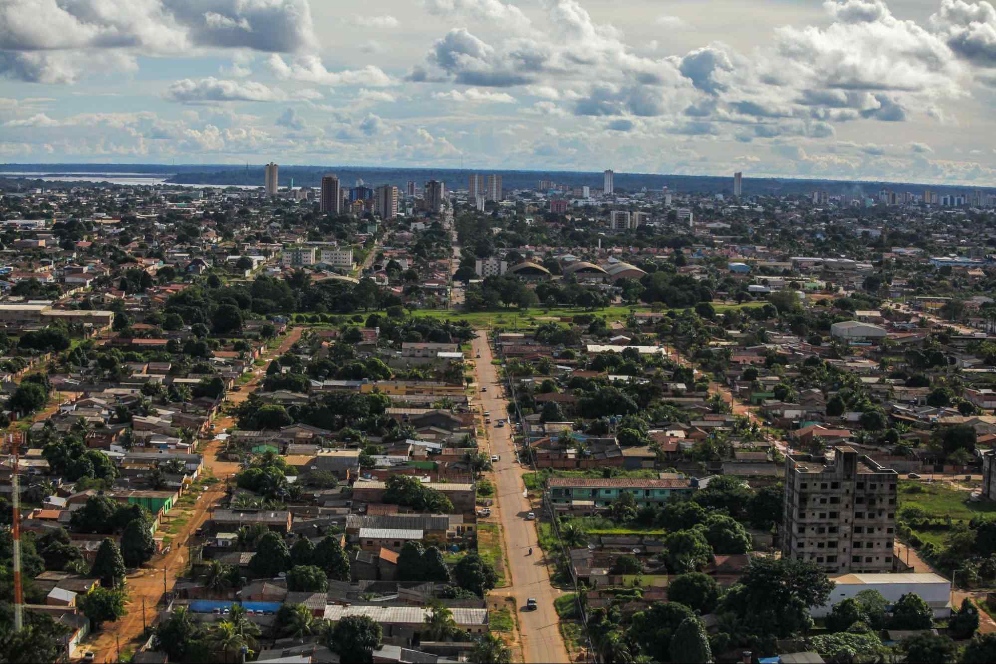 Vista aérea da cidade de Porto Velho, Rondônia. A paisagem urbana é bastante arborizada e composta principalmente por construções baixas. Em segundo plano, aparecem alguns prédios maiores e uma parte do rio
