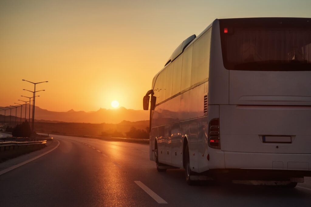 Ônibus de turismo na estrada com o pôr do sol ao fundo