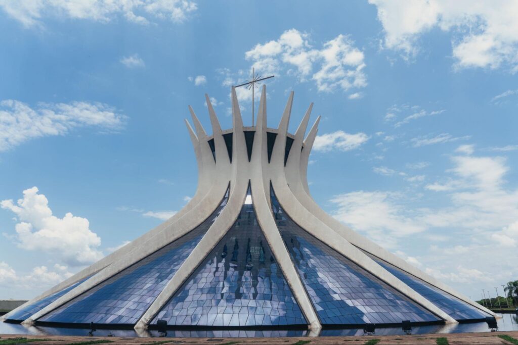 Parte externa da Catedral Metropolitana Nossa Senhora Aparecida, ou Catedral de Brasília. A construção em estilo contemporâneo tem um formato que lembra um cone. Ela é composta por arcos brancos intercalados com áreas de vidro.