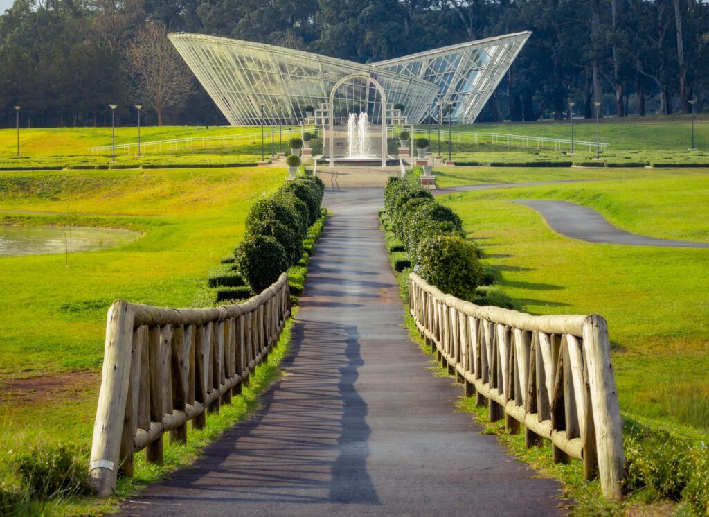 Ponte de madeira que leva a um casa de vidro em um parque em Guarapuava