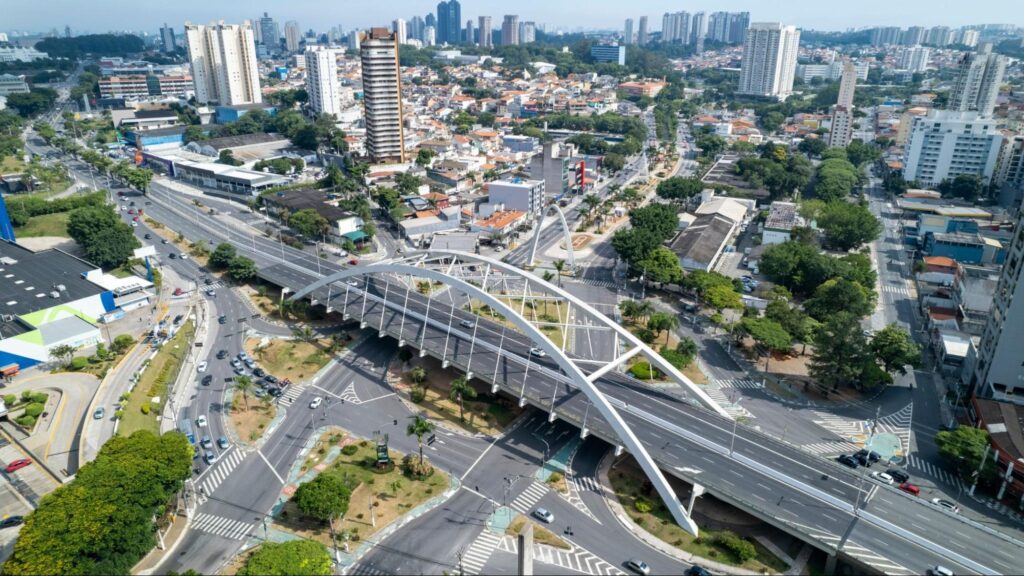 Vista aérea da cidade de Osasco, com um viaduto de estrutura metálica centralizado na imagem. Diversos prédios ao fundo e árvores nas ruas.