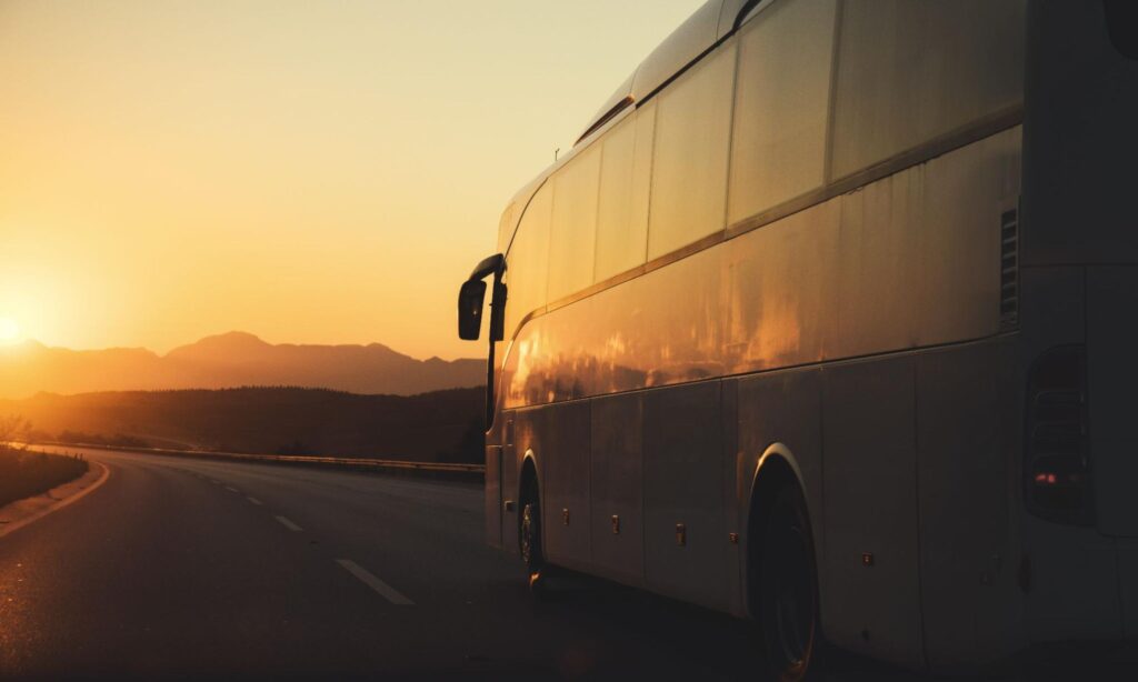Lateral de um ônibus andando em uma estrada no pôr do sol