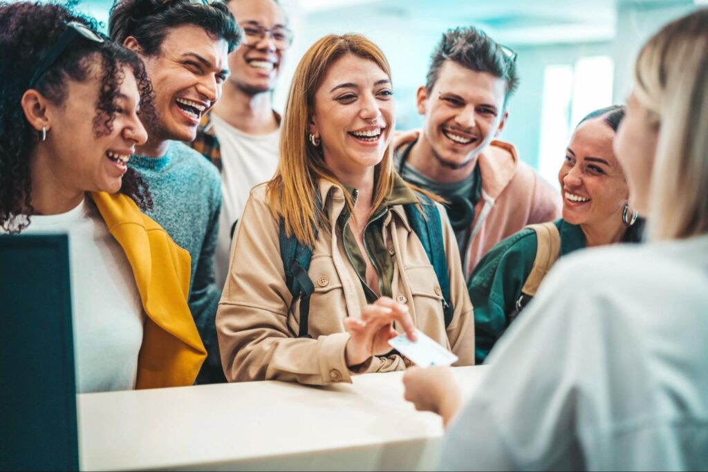 Pessoas em um balcão, sorrindo enquanto fazem checkin em um hostel