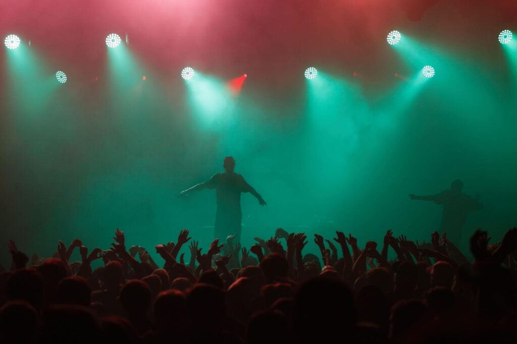 Palco com cores e fumaça de gelo seco, mostrando a silhueta de um artista que canta para uma multidão